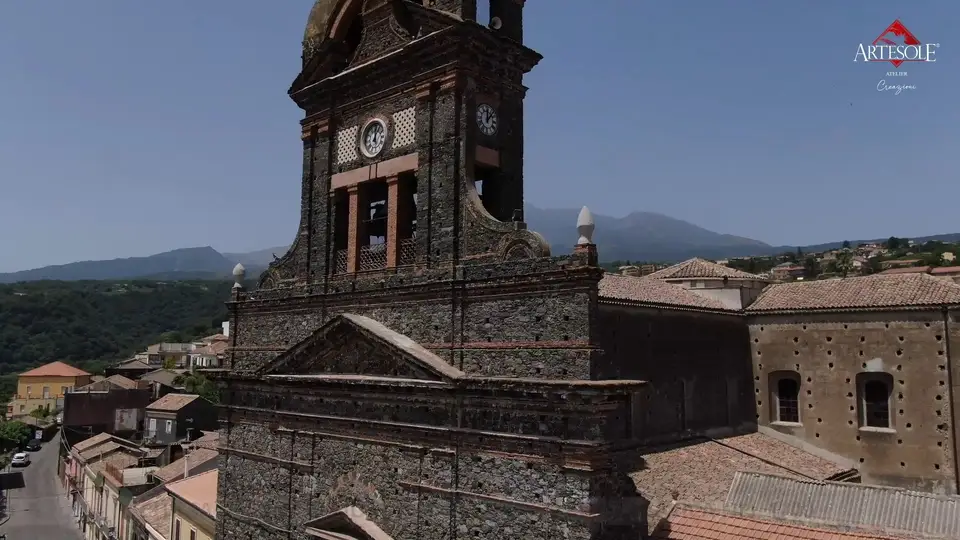 Facciata e campanile in pietra lavica della Chiesa Madre di Sant’Alfio, con l’Etna sullo sfondo Facciata e campanile in pietra lavica della Chiesa Madre di Sant’Alfio, con l’Etna sullo sfondo