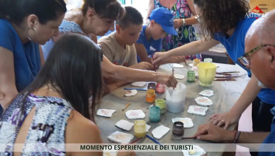 Partecipanti decorano piccoli manufatti al tavolo del laboratorio Artesole Partecipanti decorano piccoli manufatti al tavolo del laboratorio Artesole