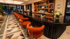 Lounge bar con bancone nero in pietra lavica ceramizzata e sedute arancioni