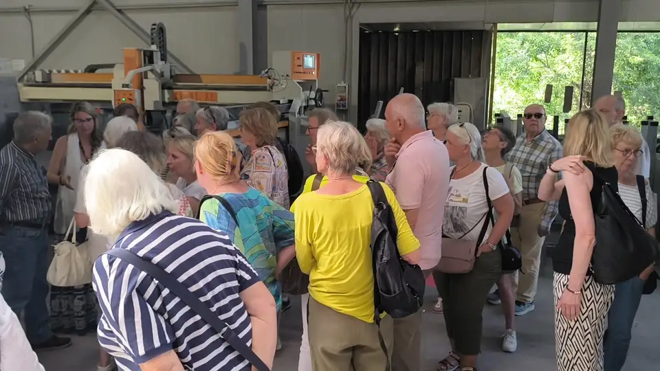 Gruppo di visitatori nel reparto con macchinari per la lavorazione della pietra