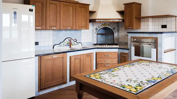 Cucina in finta muratura Liberty: composizione angolare con ante in legno e tavolo in pietra lavica decorata