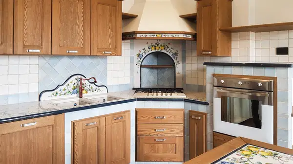 Cucina in finta muratura Liberty: zona cottura angolare e forno rialzato tra i mobili in legno