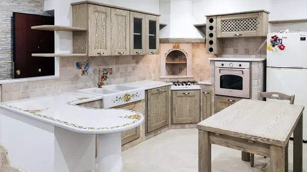 Cucina in finta muratura Venezia: composizione angolare con penisola curva decorata e ante in legno chiaro