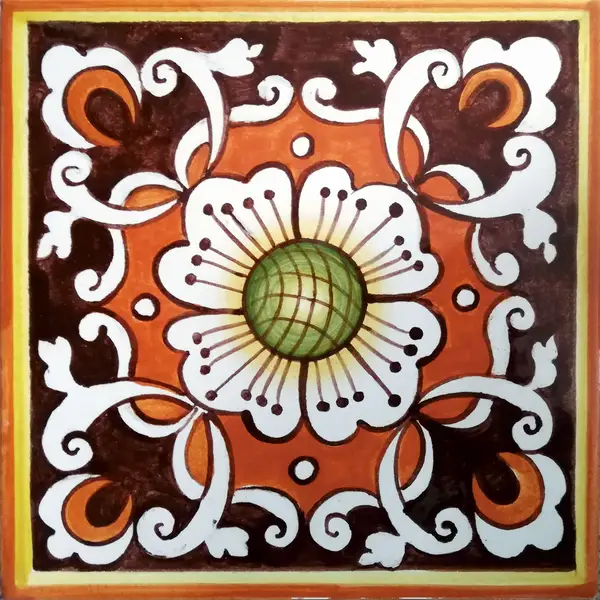 Mattonella decorata con un fiore bianco dal centro verde, volute bianche e forme arancio su fondo marrone, con bordo color ocra