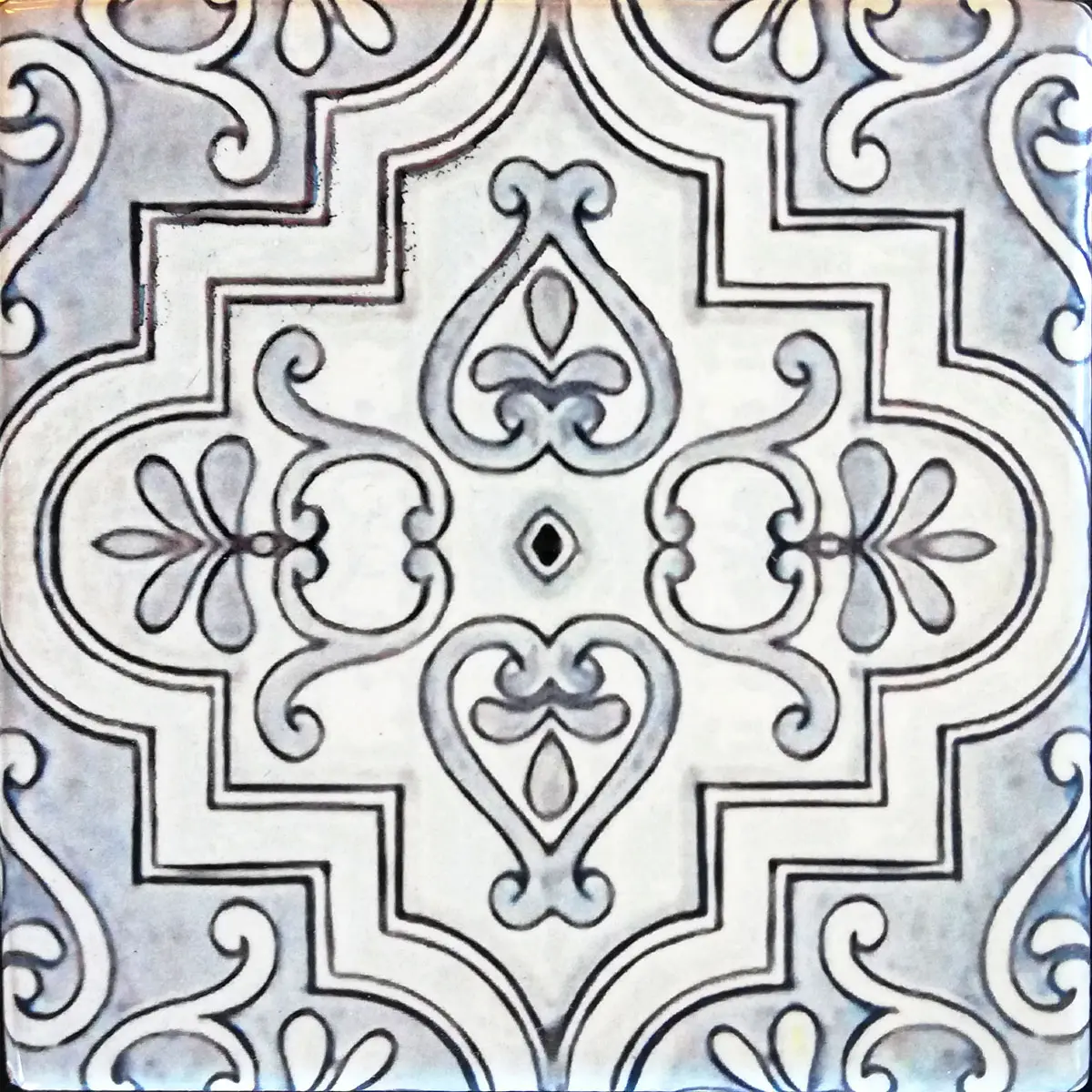 Mattonella decorata con cornice geometrica a gradini, foglie e volute grigie su fondo chiaro