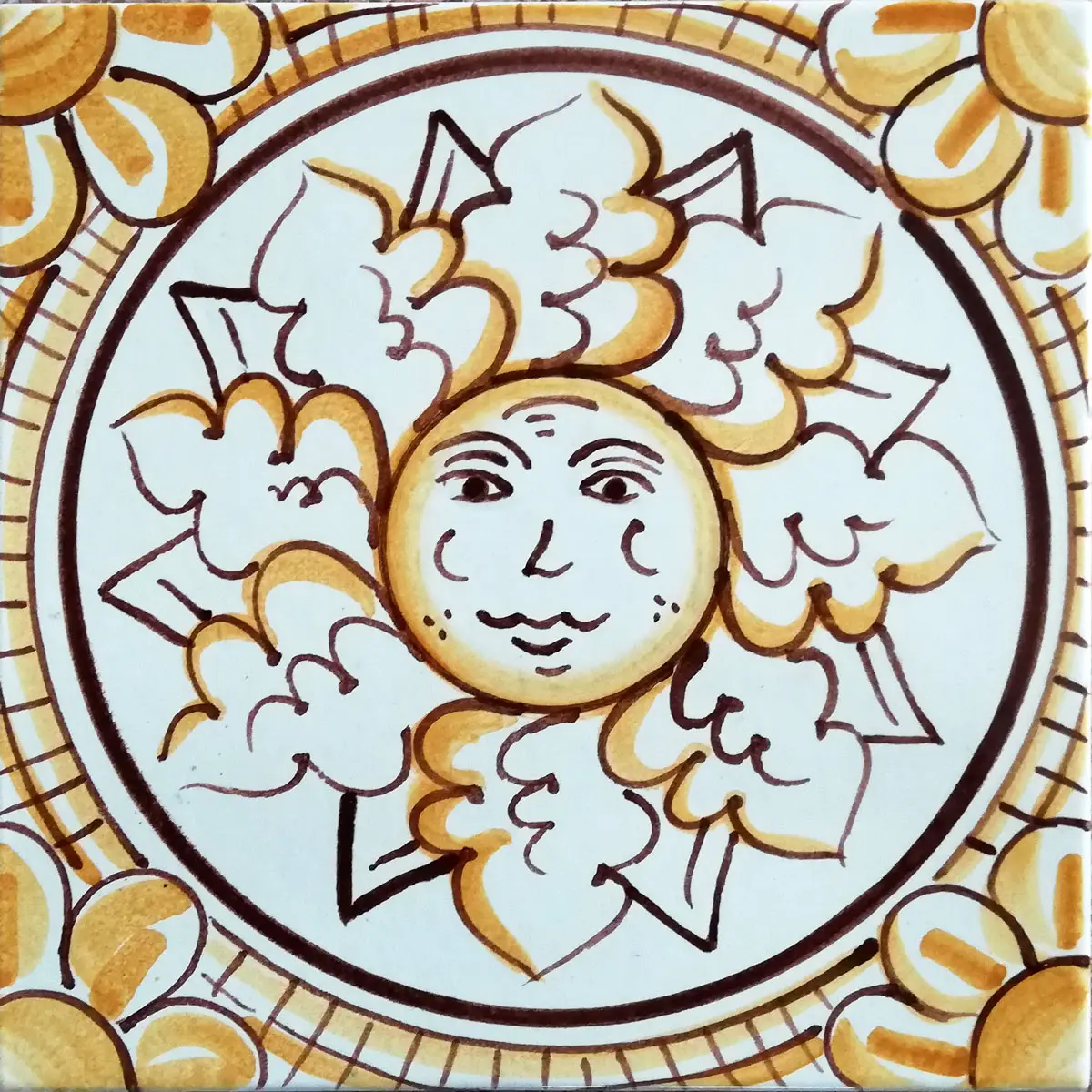 Mattonella decorata con sole dal volto umano, raggi bianchi e contorni ocra in una cornice circolare