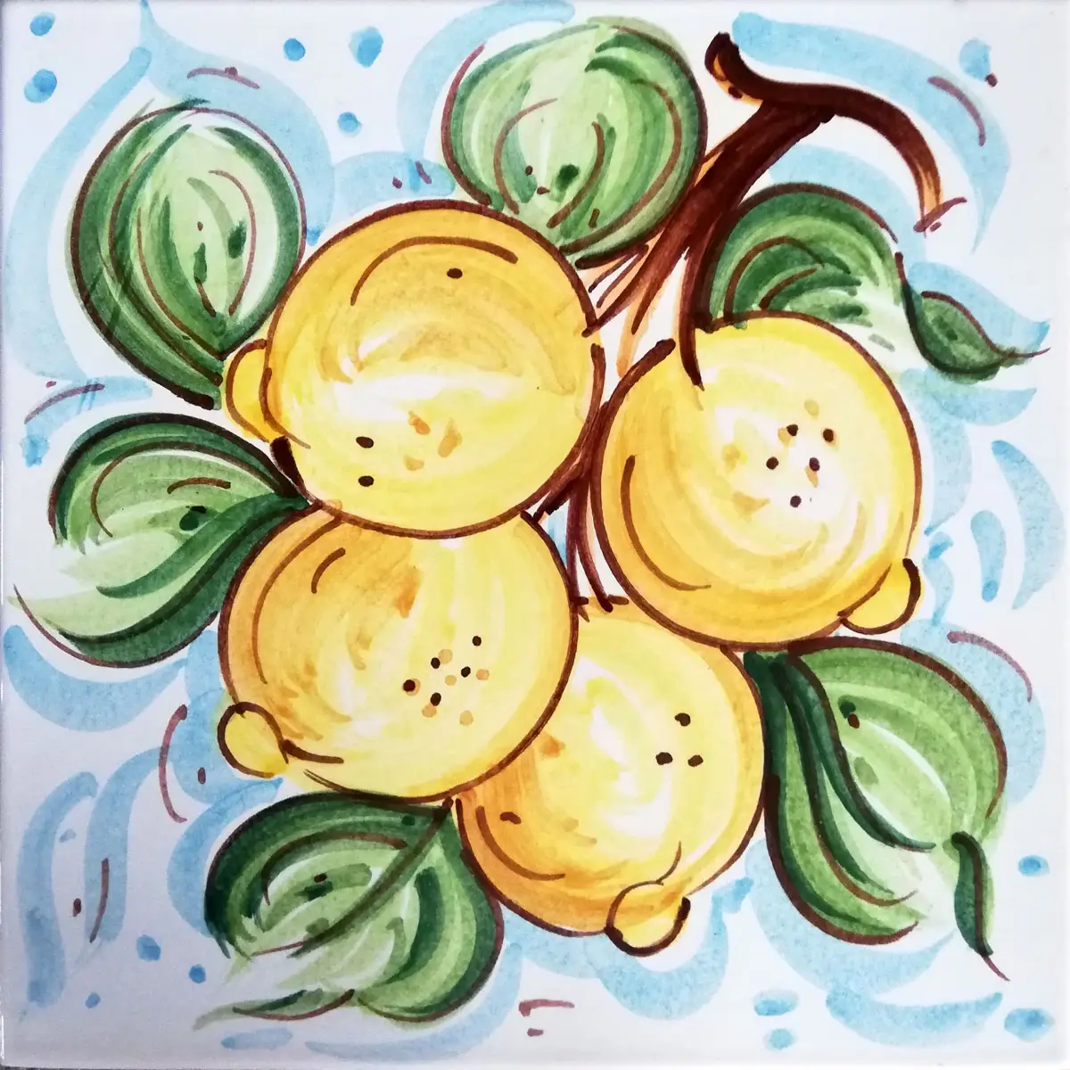 Mattonella decorata con tre limoni gialli e foglie verdi su fondo azzurro