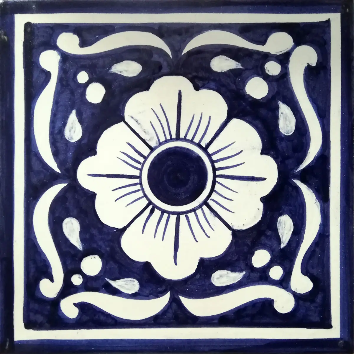 Mattonella decorata con grande fiore bianco e volute bianche su fondo blu scuro