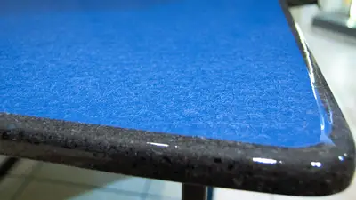 Dettaglio del piano blu lucido e del bordo scuro del tavolo moderno in pietra lavica