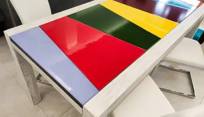 Piano del tavolo in legno con inserti in pietra lavica a fasce rosse, gialle, verdi e viola