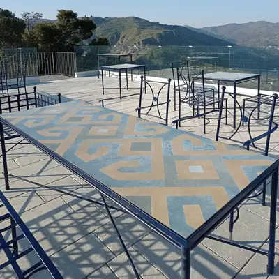 Tavolo rettangolare in pietra lavica con decoro geometrico in fotoceramica su una terrazza panoramica