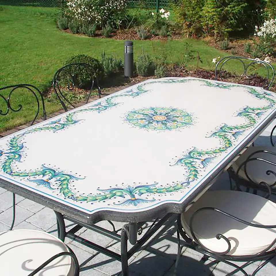 Tavolo da giardino in pietra lavica con bordo sagomato, volute turchesi e base in ferro
