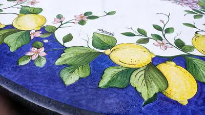 Dettaglio del tavolo in pietra lavica Limoni e Glicine in Blu, con frutti gialli e fiori chiari su fondo blu.
